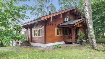 A wooden cabin with a porch, a chimney, and a small garden area.