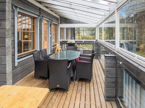 A covered outdoor patio with a round table and chairs, a grill, and a view of the surrounding area.