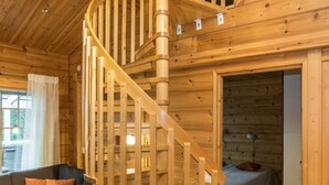 A wooden interior with a spiral staircase, a sofa, and a bed.
