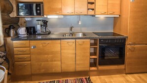 A compact kitchen with wooden cabinets, a stainless steel sink, a Bosch dishwasher, and a coffee maker. - Örtsylä a by Interhome (Salla)