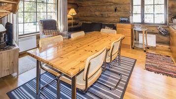 A wooden dining table with chairs, a sofa, and a kitchen area with a stove.