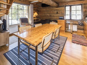 A wooden dining table with chairs, a sofa, and a kitchen area with a stove.