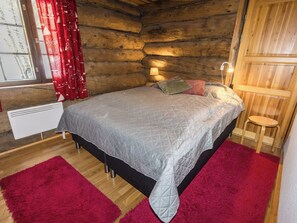 A cozy bedroom with a bed, red curtains, a wooden headboard, and a small stool. - Örtsylä a by Interhome (Salla)