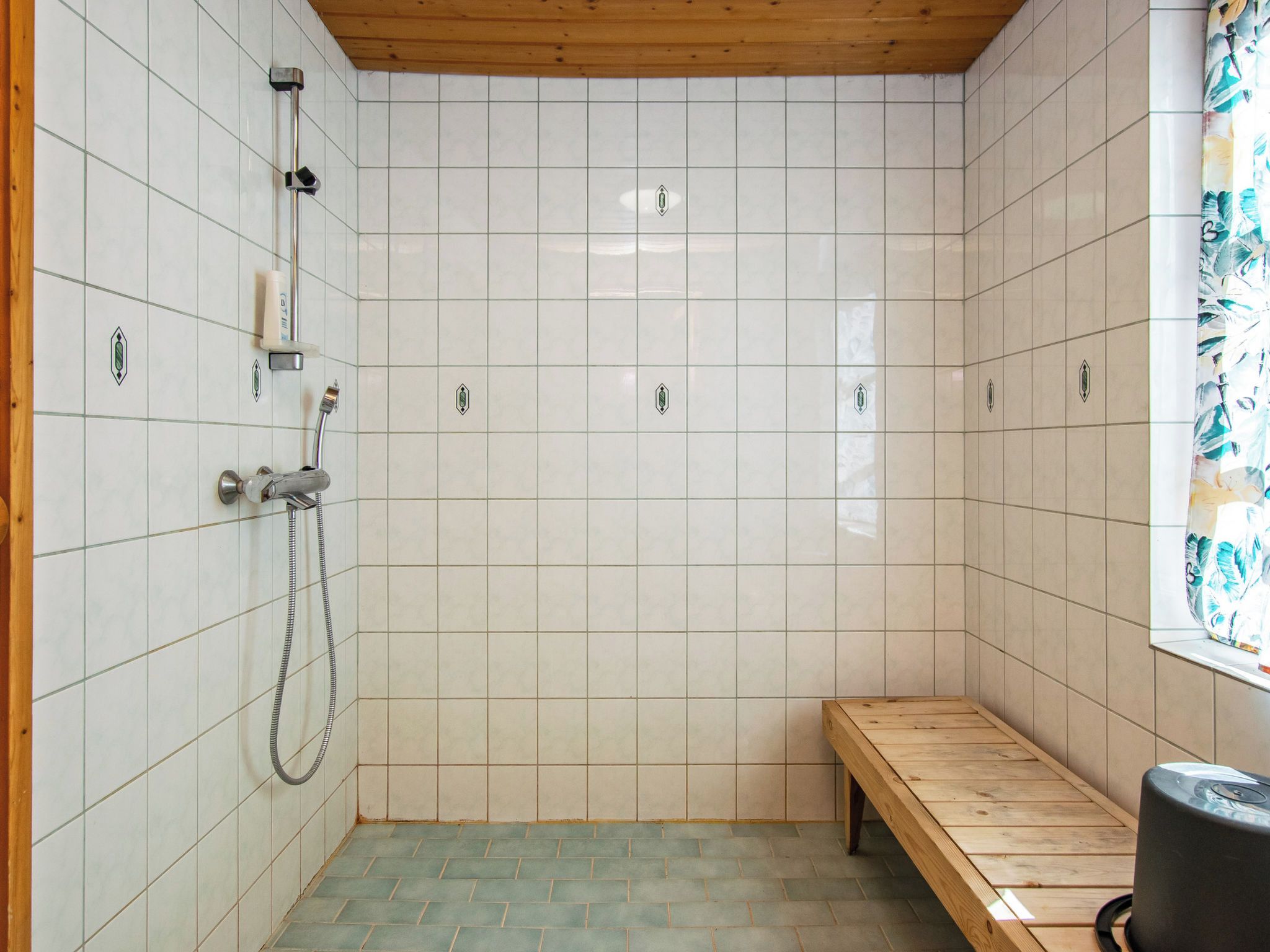 Zona de ducha con paredes de azulejos, un banco y techo de madera.