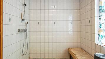 Zona de ducha con paredes de azulejos, un banco y techo de madera.