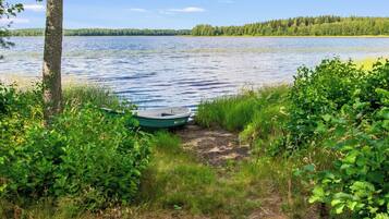 Un sentier longeant le bord du lac, avec un bateau amarré sur la rive, le tout entouré d’une végétation luxuriante.