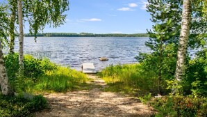 A natural lakeside path leading to a wooden dock.