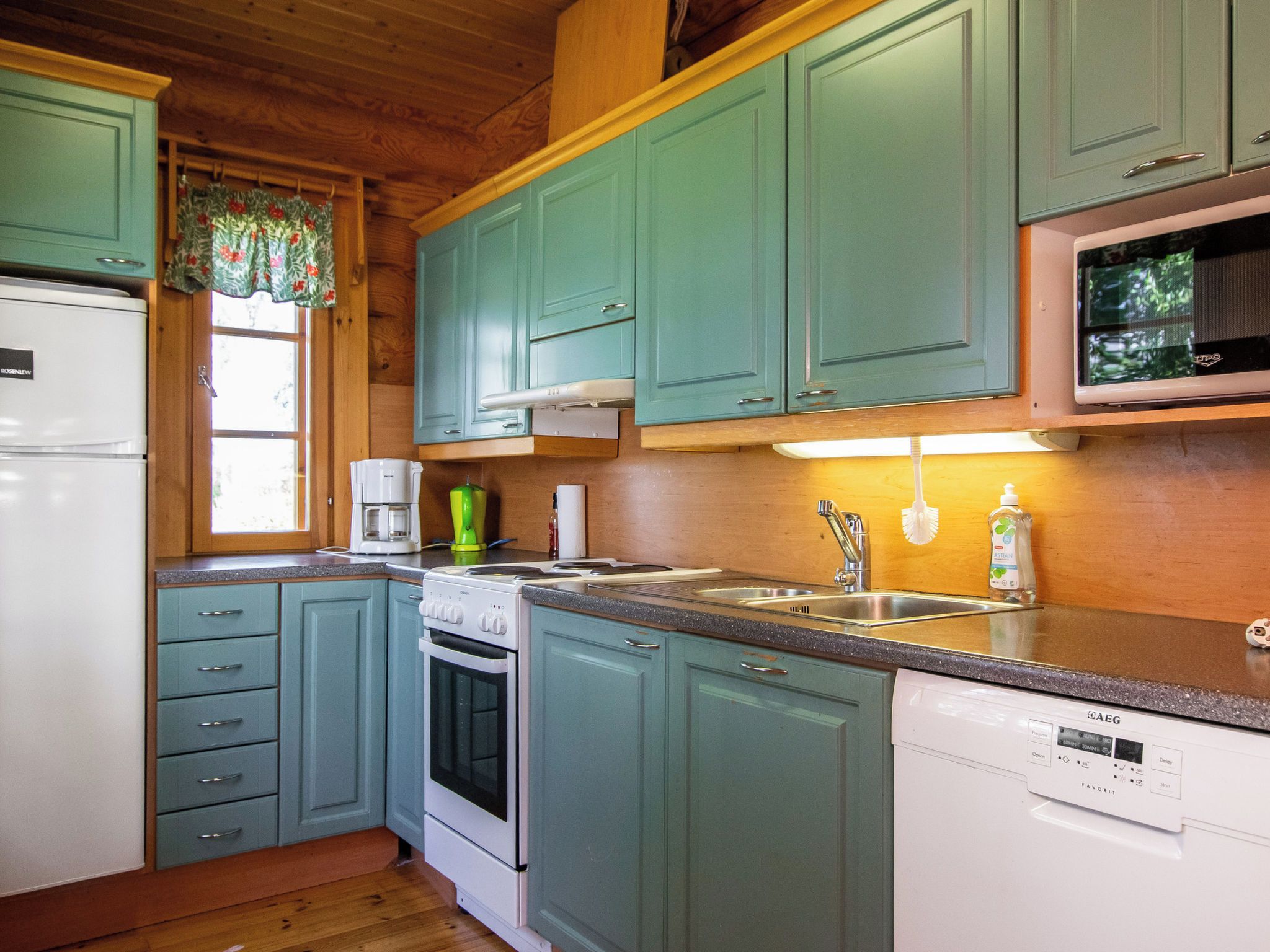 A kitchen with teal cabinets, a white refrigerator, a stove, a microwave, and a dishwasher.