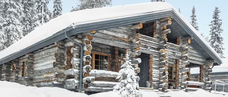 Una baita di legno con tetto imbiancato dalla neve e un portico in legno.