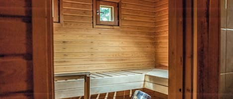 Interior de una cabaña de madera con literas, un ventanal pequeño y un cuadro en la pared.