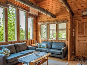 A cozy cabin interior with a sofa, a coffee table, and a window overlooking greenery. - Vacation home Kallio by Interhome (Kuusamo)