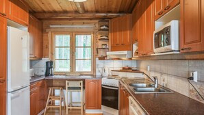 Una cocina con armarios de madera, un refrigerador, un microondas, una estufa y un lavamanos.