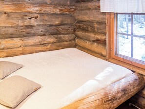 Una habitación tipo cabaña de madera con una cama, almohadas y una ventana.