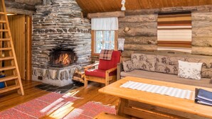 Interior acollidor d'una cabana de fusta amb una llar de pedra, mobles de fusta i una cadira vermella.