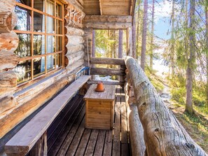 A log cabin with a wooden bench and a table, surrounded by a forest. - Retkietappi kelopirtti by Interhome (Kuusamo)
