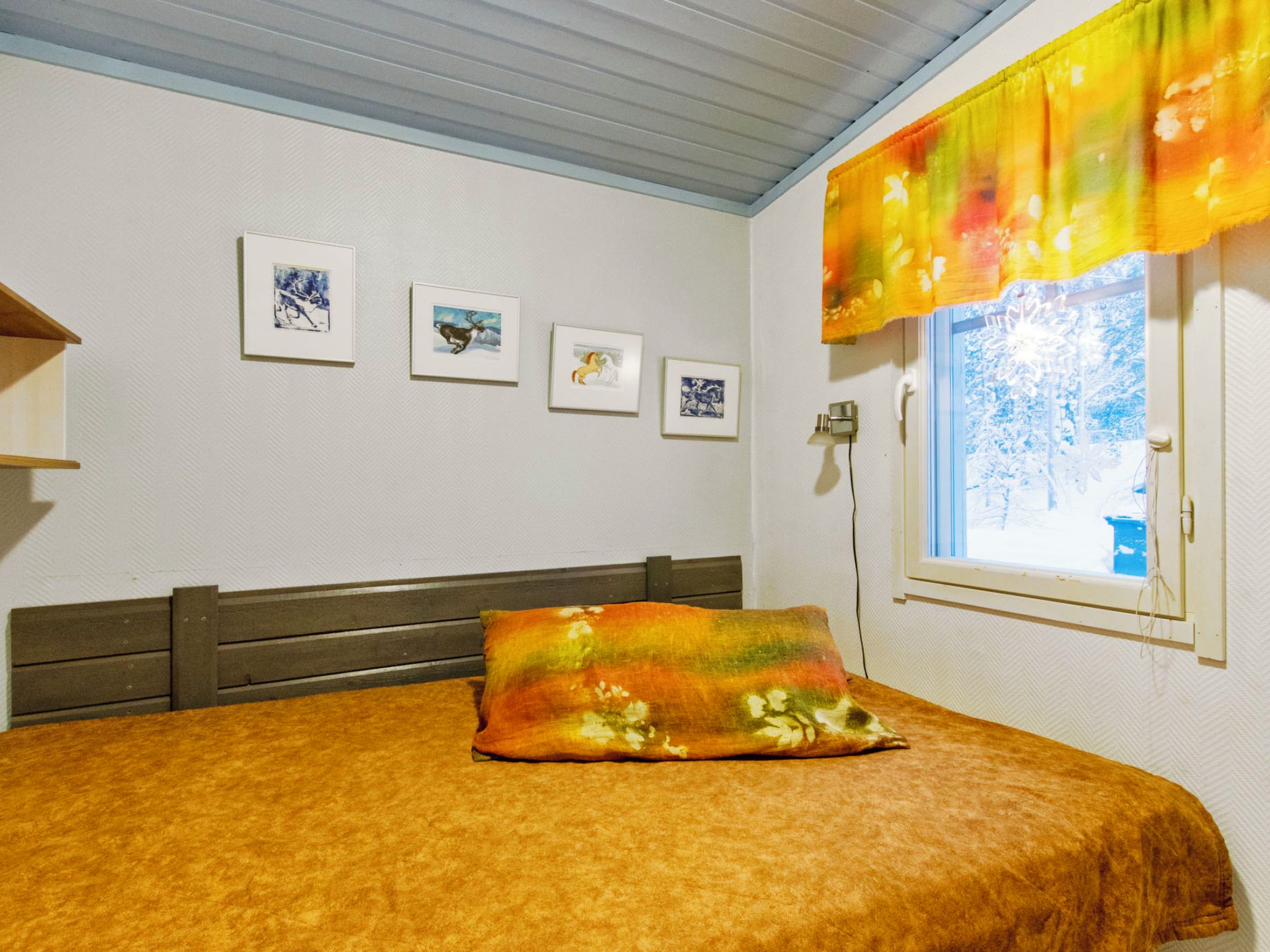 Una camera da letto con un letto, una finestra vista e tre quadri appesi al muro.