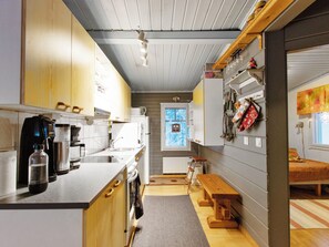 A compact kitchen with wooden cabinets, a built-in oven, a sink, and a window with a view. - Jousimaja by Interhome (Kolari)