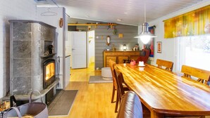 Een gezellig interieur met een open haard, een houten eettafel en een keukenhoek.