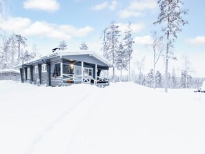 A log cabin with a porch, surrounded by snow-covered trees. - Jousimaja by Interhome (Kolari)
