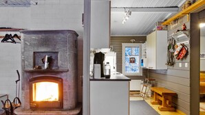 Een moderne keuken met een stenen openhaard, houten kasten en een raam met uitzicht op sneeuw.