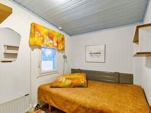 A bedroom with a bed, a window, a radiator, a wall-mounted shelf, and a framed picture. - Jousimaja by Interhome (Kolari)