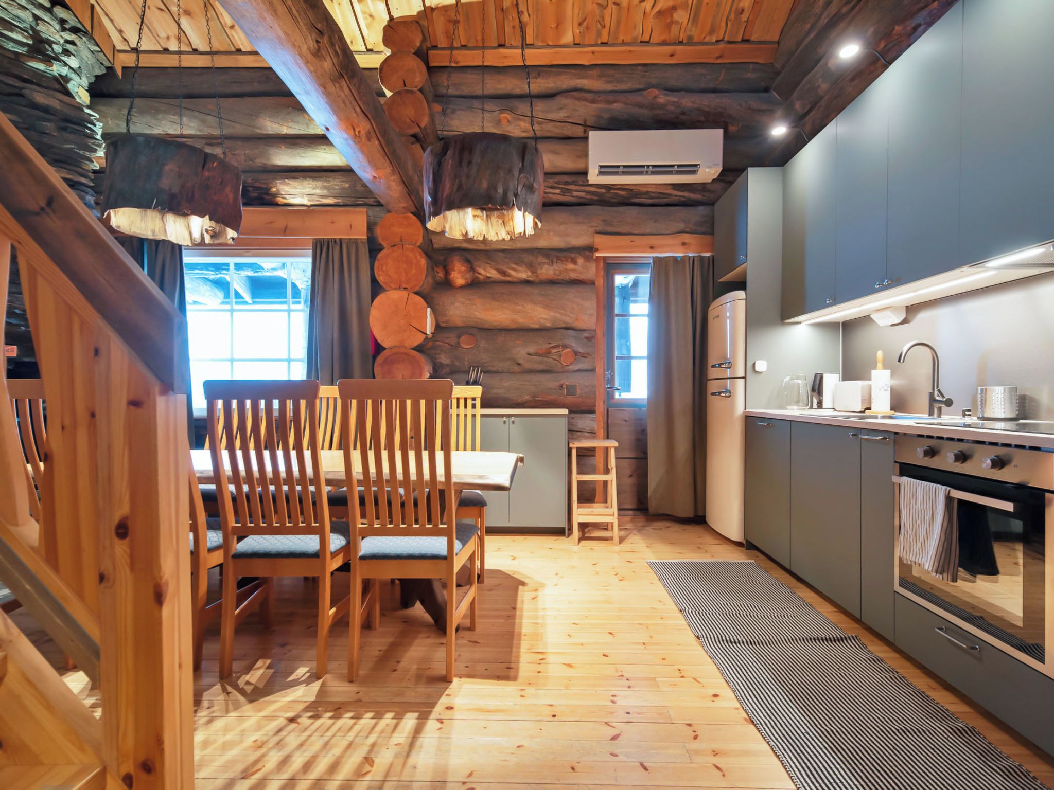 A cabin interior with a dining area, kitchen, and log walls.