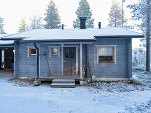 A small, single-story wooden cabin with a front porch, a chimney, and a snow-covered landscape. - Pohjaskoti b by Interhome (Kuusamo)