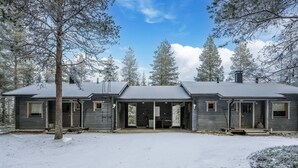 A two-story log cabin with a covered porch and a snow-covered ground.