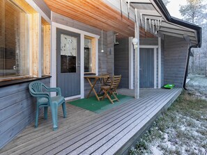 A wooden deck with a table and chairs, a door, and a window with blinds. - Pohjaskoti b by Interhome (Kuusamo)