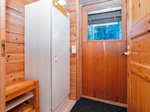 A wooden interior with a white door, a small wooden bench, and a window with a view of trees. - Pohjaskoti b by Interhome (Kuusamo)