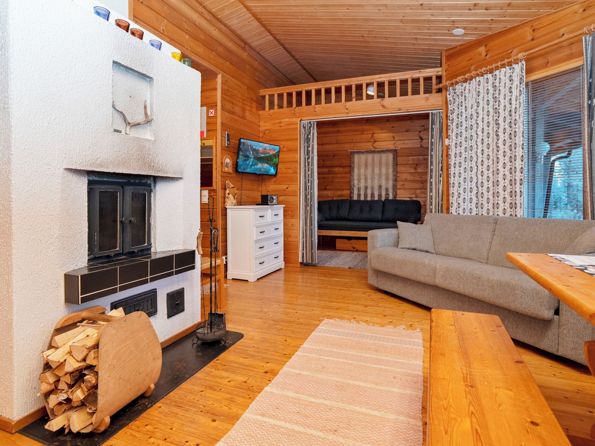 Interior acogedor de una cabaña con chimenea, muebles de madera y un televisor.