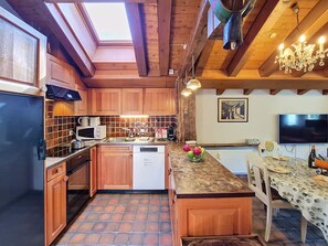 Une cuisine dotée de meubles en bois, d’un four à micro-ondes, d’un évier et d’un coin repas avec une table et des chaises.