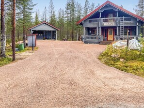 Eine Holzhütte mit rotem Dach und Veranda, umgeben von einem Wald.