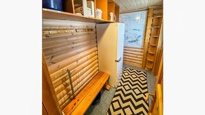 L'intérieur d'un chalet en bois, avec un banc, des étagères et un tapis à motifs.