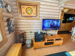 A log cabin interior with a wooden entertainment center, a television, and a wall clock.