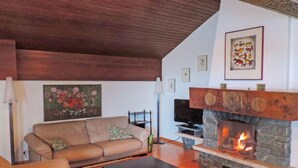 A cozy living room with a stone fireplace, a sofa, and a television.