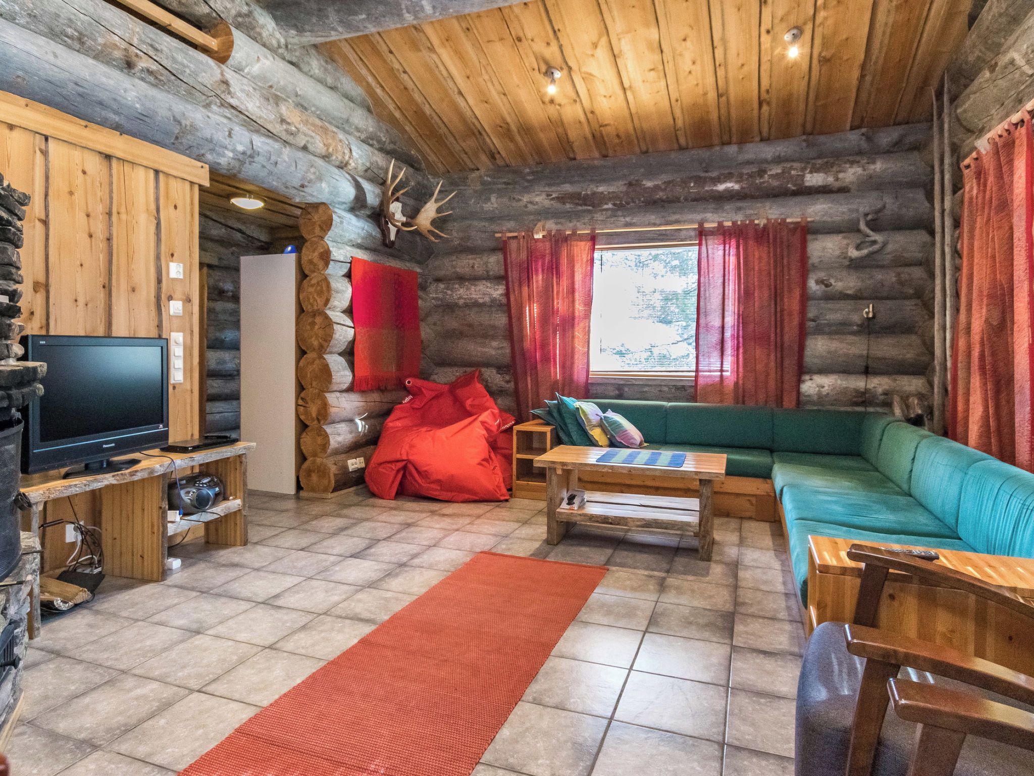 Een vakantiehuisje interieur met een televisie, bank en houten meubels.