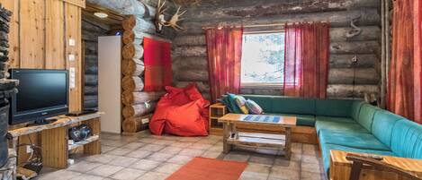 A log cabin interior with a television, sofa, and wooden furniture.