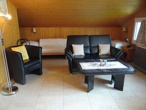 A cozy living room with a sofa, armchairs, a coffee table, and a lamp.
