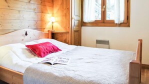Una camera da letto in stile baita con un letto singolo, un comodino con una lampada e una finestra con tende.
