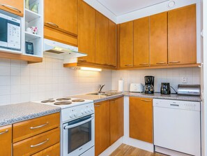 Una cocina con armarios de madera, estufa Bosch, lavavajillas y cafetera.