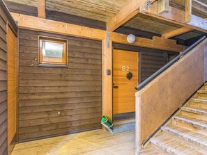 Un interior de madera con una puerta de madera marcada con el número '32', una ventana y una escalera.