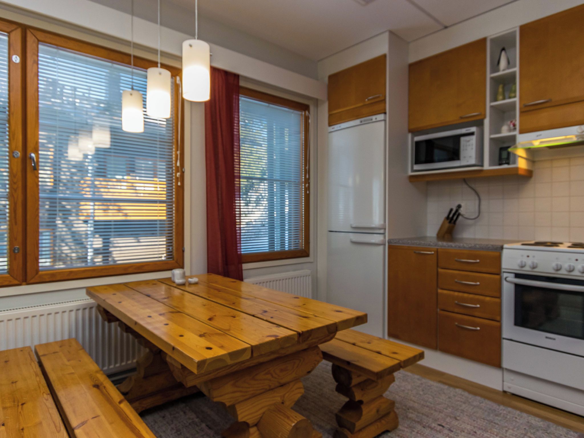 Une cuisine avec des meubles de rangement en bois, un réfrigérateur blanc, un four à micro-ondes et une cuisinière.