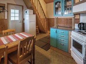 A kitchen with wooden cabinets, a stove, a refrigerator, and a dining table with chairs. - Satulinna by Interhome (Kemiönsaari)
