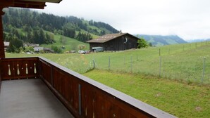 Een balkon met uitzicht op een landelijk landschap, met een schuur en glooiende heuvels.