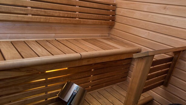 A sauna with wooden benches and a metal heater.