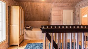 A wooden interior with a bed, wardrobe, and a staircase.