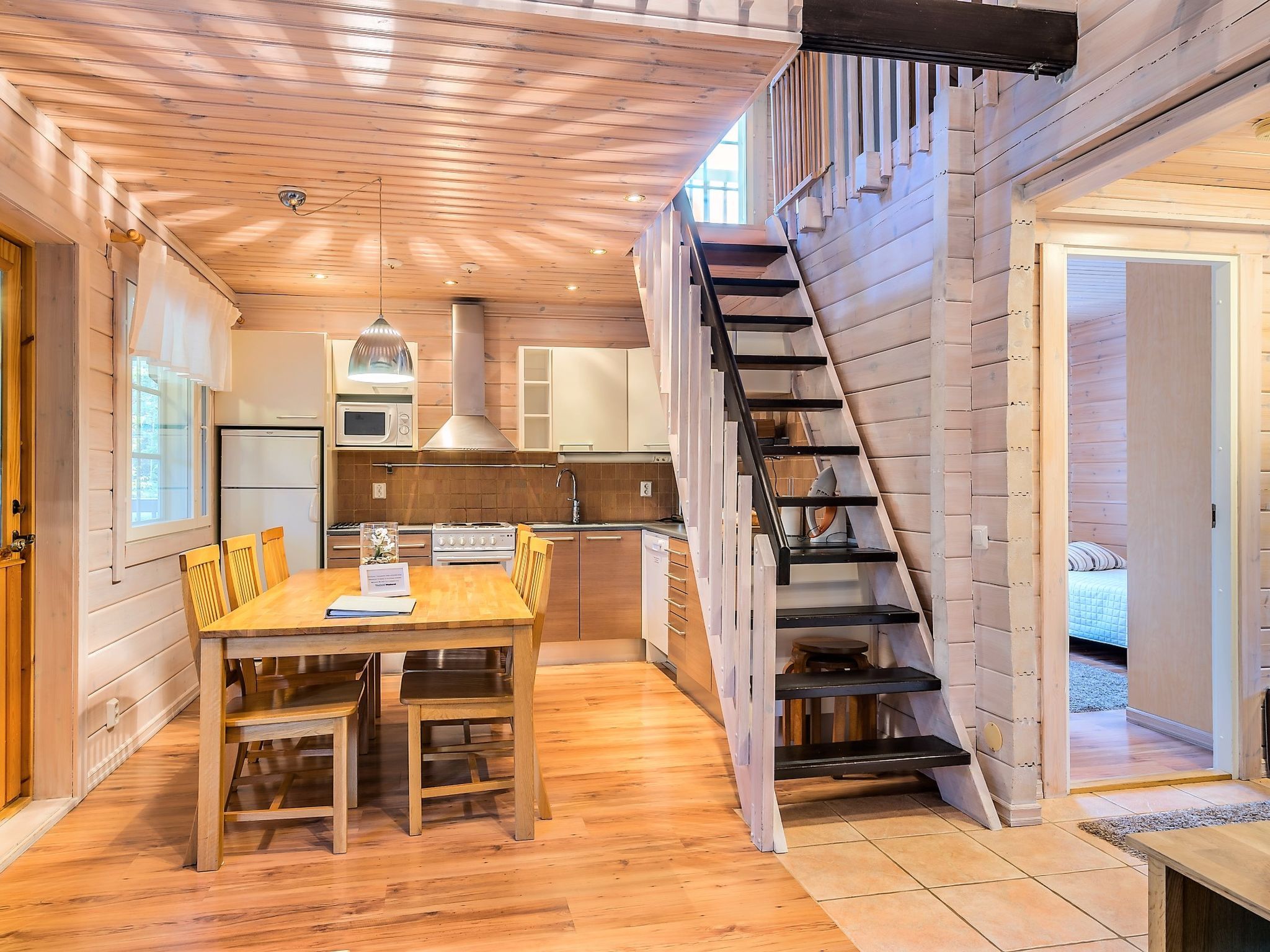 Un interior de madera con comedor, cocina y una escalera.