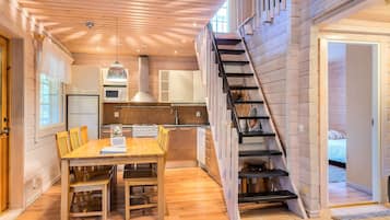 Un interior de madera con comedor, cocina y una escalera.