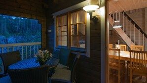 Una cabaña de madera con comedor, escaleras y vistas al bosque.